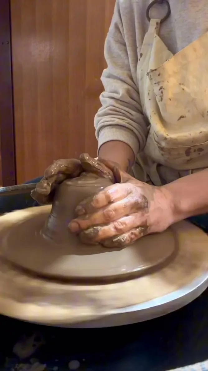 Mãos dando forma ao barro no torno.