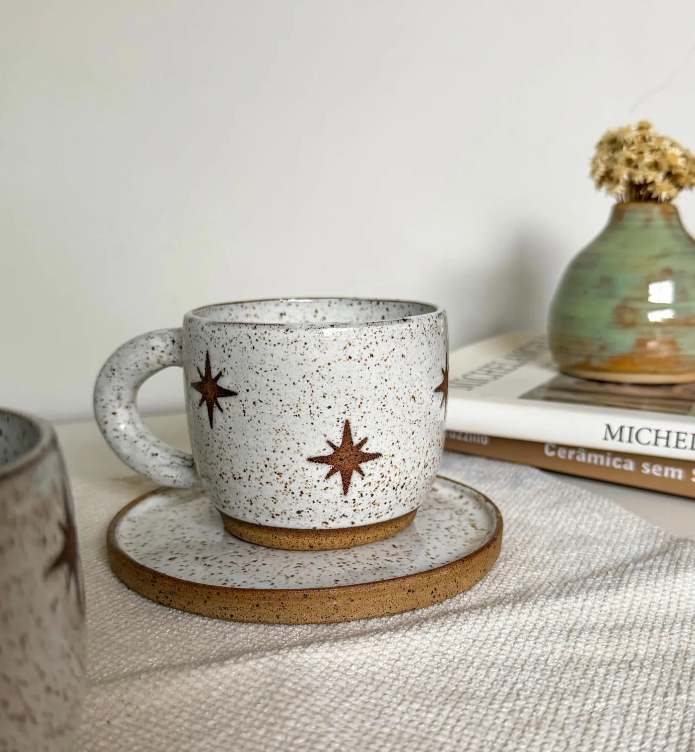 Caneca Estrela sobre o prato de cerâmica, ao lado de livros.